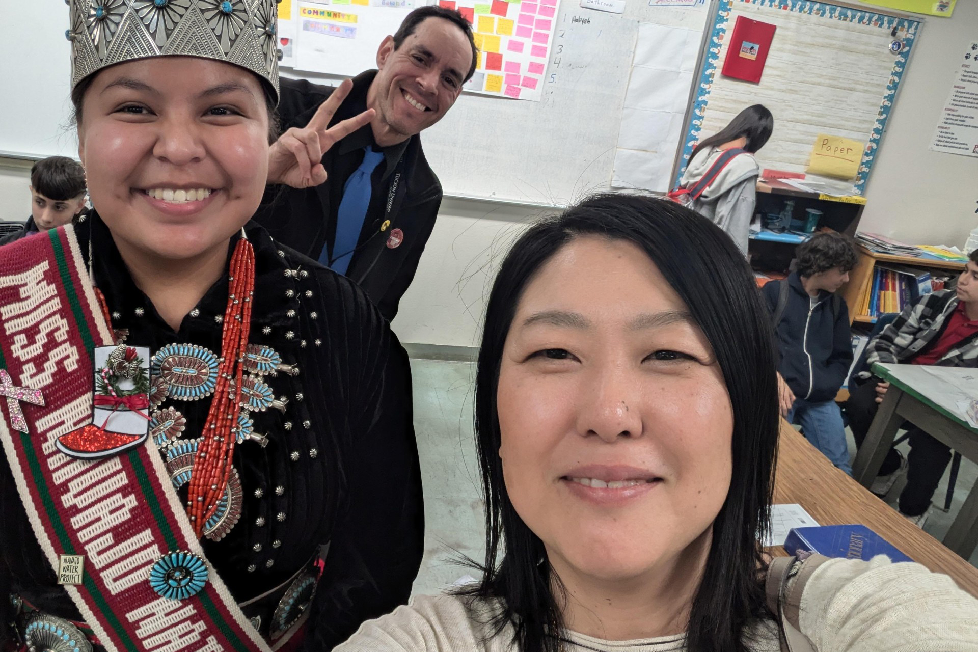 Miss Navajo Nation smiles for a photo with a woman and a man making a peace sign