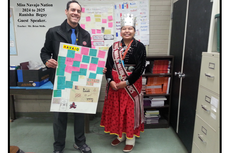 Miss Navajo Nation smiles for a photo with a man holding a poster with Navajo facts on it