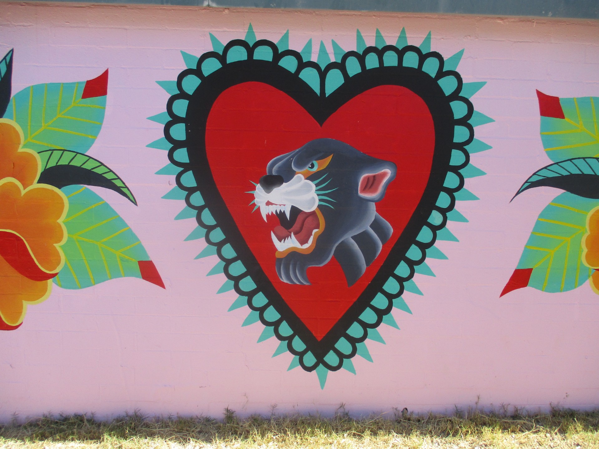 A mural of Pistor's panther mascot surrounded by a red heart and tropical flowers on a pink wall