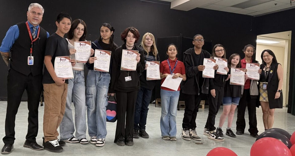 Two teachers and a group of students pose with their award certificates