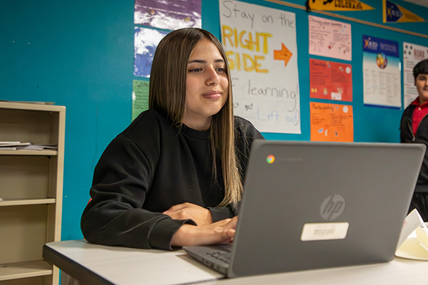 A preteen girl looks at her laptop