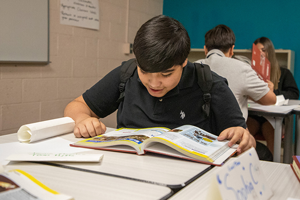 A preteen boy excitedly looks through his textbook