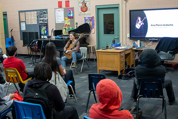 Middle schoolers listen to a professional guitarist