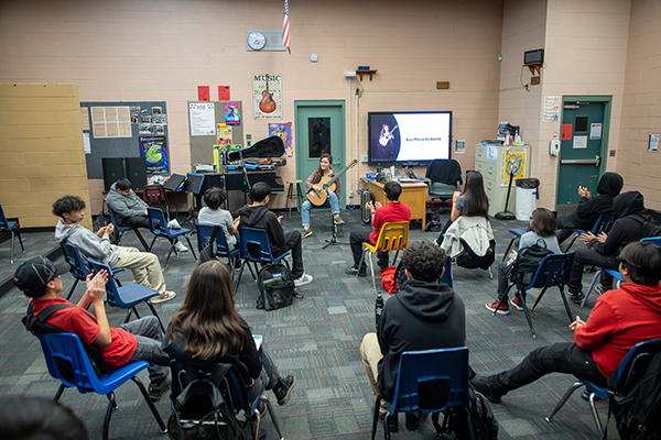 Middle school classroom with a woman teaching guitar