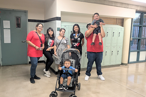 A family smiles in the school hallway in front of lockers